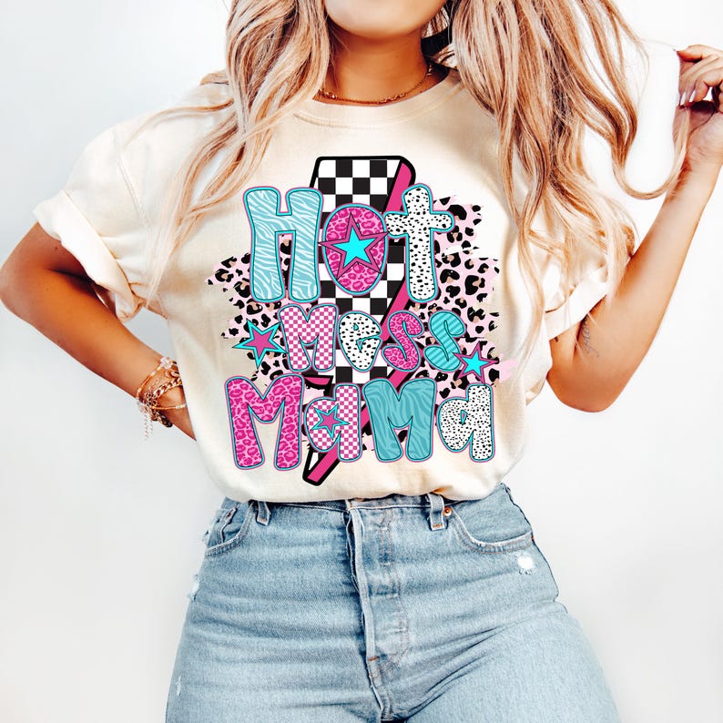 May include: A white t-shirt with a pink, blue, and black graphic design that says "Hot Mess Mama" with a lightning bolt and stars.