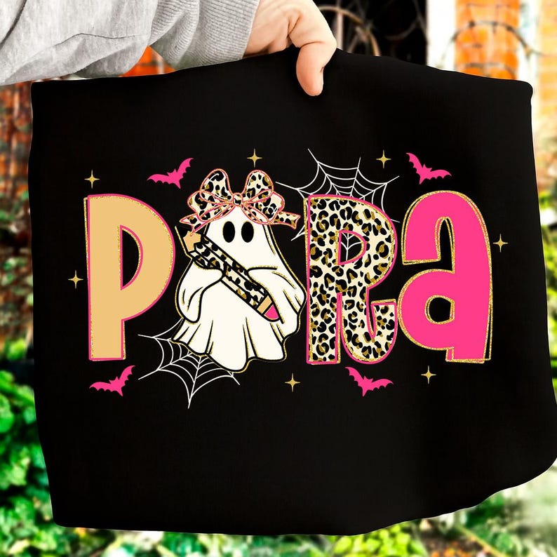 Pu&ograve; includere: T-shirt nero con la scritta "PARA" in beige, stampa leopardata e rosa. Un fantasma con un fiocco e una matita &egrave; al centro. Pipistrelli rosa e ragnatele decorano la maglietta, perfetta per Halloween.