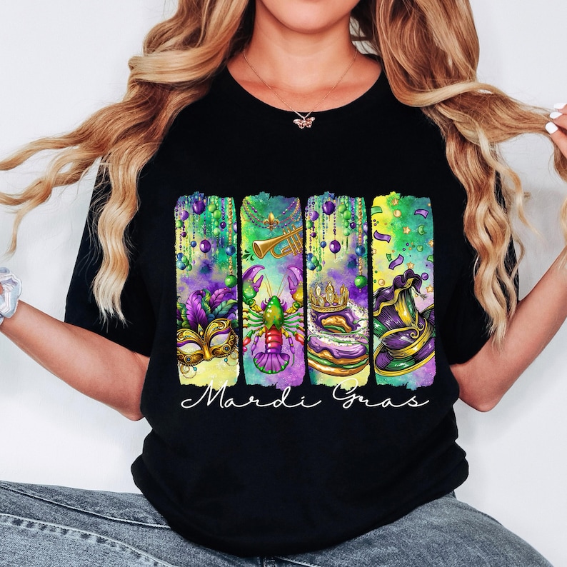 May include: Black t-shirt with a colorful Mardi Gras design featuring a mask, a crawfish, a king cake, and a hat. The text "Mardi Gras" is printed below the design.