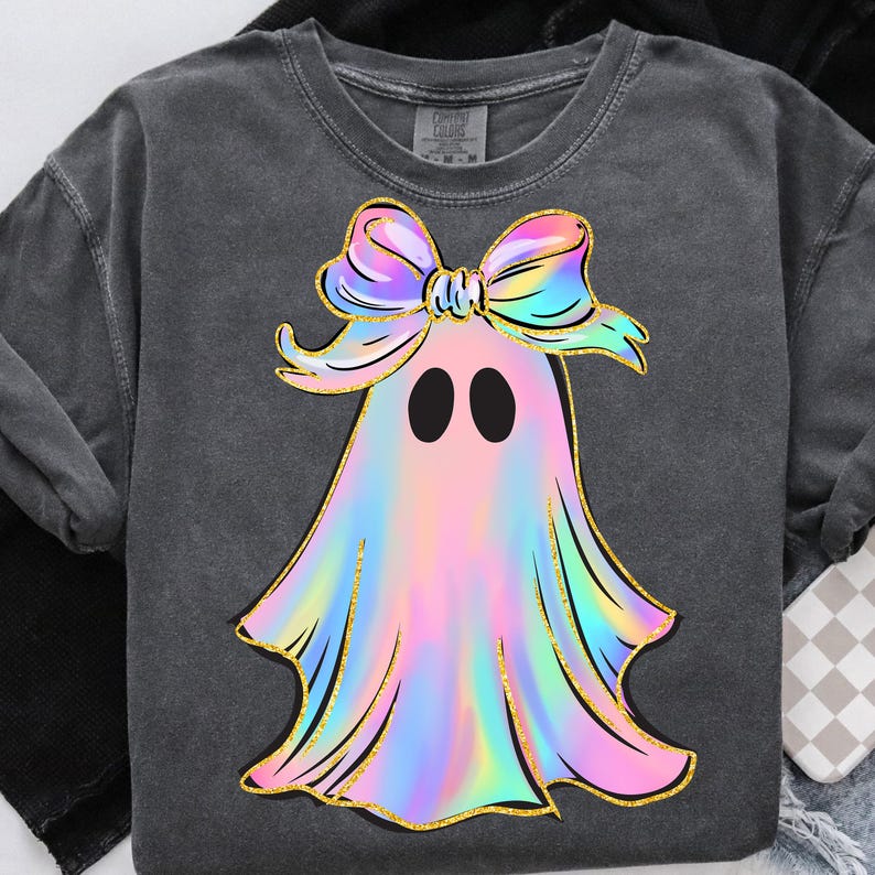 May include: Dark grey sweatshirt featuring a colorful ghost design. The ghost has a rainbow-colored body, black eyes, and a large bow. The design is outlined in gold glitter.