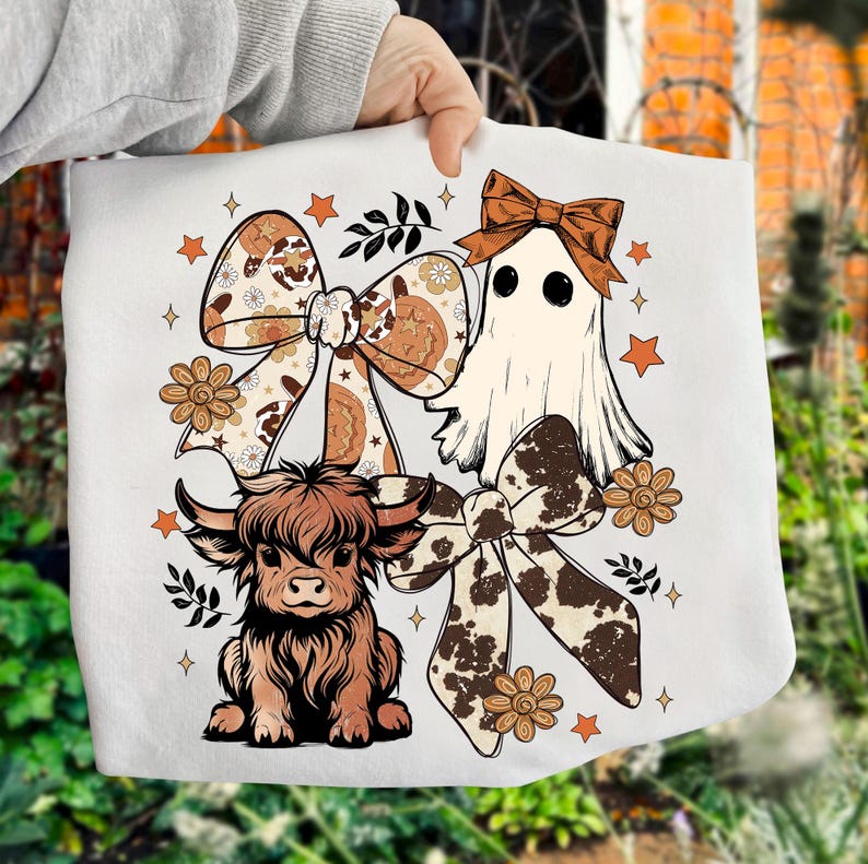 Op de afbeelding: Witte draagtas met een cartoon spook, een Schotse hooglander en twee grote strikken met bloemen- en koeienprintpatronen. Het ontwerp bevat sterren en bloemen in bruin- en oranje tinten.
