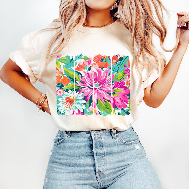 May include: A white t-shirt with a colorful floral print. The print features pink, green, blue, and orange flowers.