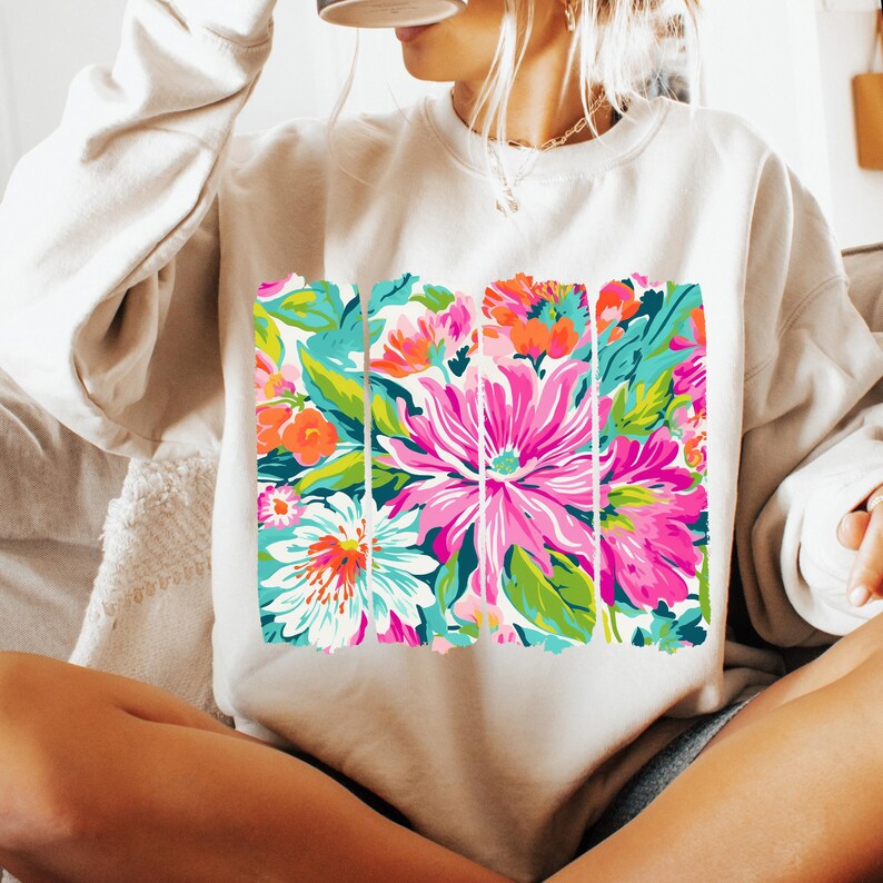 May include: A white sweatshirt with a colorful floral print. The print features pink, green, blue, and orange flowers.
