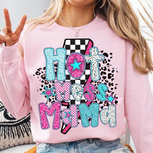 May include: Pink sweatshirt with a graphic design of a lightning bolt with the words "Hot Mess Mama" in colorful letters with a checkered, leopard print, and zebra print pattern.