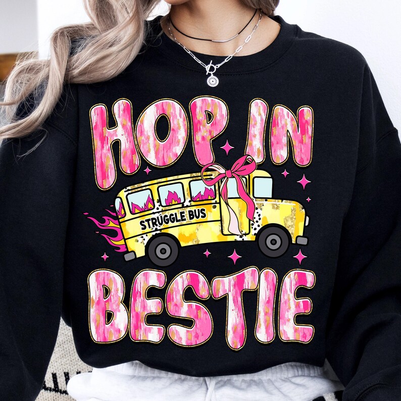 May include: Black sweatshirt with a pink and yellow graphic design. The graphic features a school bus with the words "Struggle Bus" and the text "Hop in bestie".