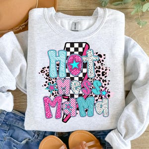 May include: A gray sweatshirt with the text "Hot Mess Mama" in pink, blue, and black letters. The letters are surrounded by a checkered pattern, animal print, and stars.