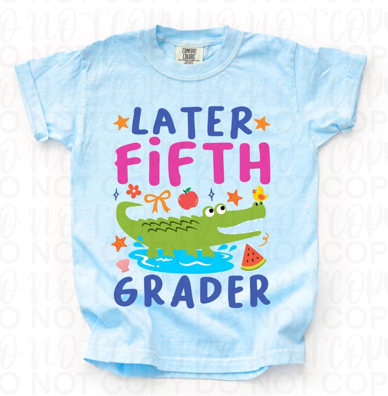 K&ouml;nnte beinhalten: Hellblaues T-Shirt mit dem Schriftzug "LATER FIFTH GRADER" in Pink und Blau. Ein gr&uuml;nes Alligatoren-Motiv, ein roter Apfel, ein gelbes K&uuml;ken und eine Wassermelone sind ebenfalls abgebildet.