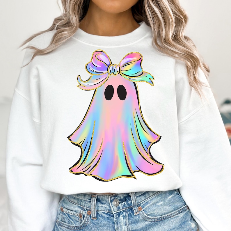 May include: White sweatshirt featuring a colorful ghost design with a bow. The ghost has a pastel rainbow color scheme with gold accents. The bow is also rainbow-colored. The design is centered on the front of the sweatshirt.