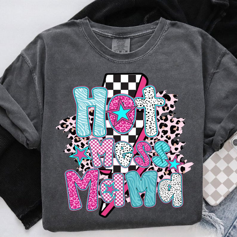 May include: A gray t-shirt with a graphic design that says "Hot Mess Mama" in pink, blue, and black letters. The graphic design includes a checkered pattern, animal print, and stars.
