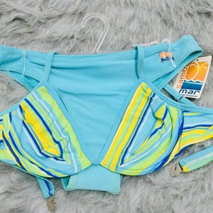 Può includere: Un top bikini azzurro con un motivo a righe multicolore giallo, verde lime e bianco. Il capo presenta spalline regolabili, una gruccia in plastica trasparente e un'etichetta bianca con la scritta mar beachwear e un logo.