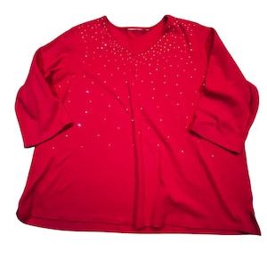 May include: A bright red, long-sleeved top with a V-neckline. The top is adorned with small, sparkling embellishments scattered across the chest and shoulders. The sleeves are three-quarter length. The fabric appears soft and comfortable.