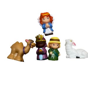 May include: A collection of miniature Christmas figurines. The set includes a camel, three wise men, an angel, and a lamb. The figurines are brightly colored and made of plastic. The angel wears a blue dress and has red hair. The wise men are dressed in purple and green robes.