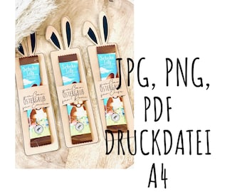 Könnte beinhalten: Drei hölzerne Geschenkkartenhalter in Hasenform mit einer Schokoladentafel darin. Jeder Halter hat einen anderen Namen: "Emilia", "Kimi" und "Lisa". Die Schokoladentafel ist eine "Schoko Lolly" und hat eine blau-weiße Verpackung mit einem Hasen darauf. Der Text auf den Haltern lautet "Ein Ban Ostergrus" (Ein Ostergruß vom Hasen).