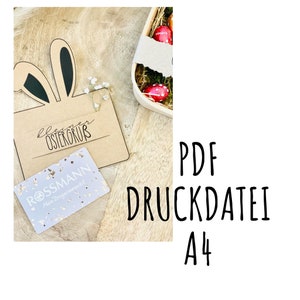 May include: A printable Easter card with bunny ears and the text "kleiner Ostergruß" on a brown background. The card is next to a gift card from Rossmann, a German drugstore chain. The text "PDF Druckdatei A4" is visible in the background.