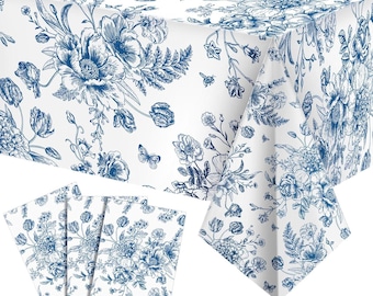 May include: White tablecloth and matching napkins with a blue floral pattern. The design features detailed illustrations of flowers, leaves, and butterflies. The tablecloth is draped over a table, and the napkins are neatly arranged.