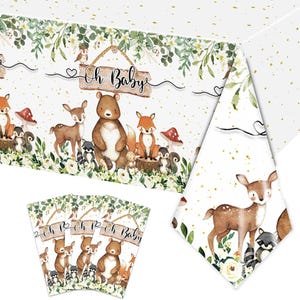 May include: A white tablecloth with a woodland baby shower theme. The tablecloth features a border of green leaves, white flowers, and woodland animals including a deer, bear, fox, and raccoon. The text "Oh Baby" is written on a wooden sign hanging from a rope. The tablecloth is decorated with gold glitter dots.