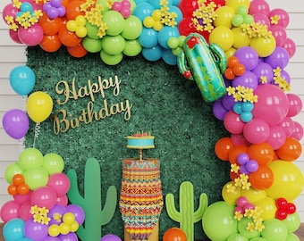 May include: A colorful balloon arch with a cactus balloon, a cake stand with a cake, and a green backdrop with the words "Happy Birthday" in gold letters.