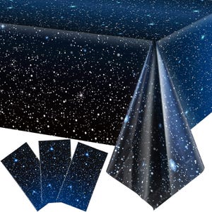May include: A dark blue tablecloth and matching placemats with a starry night design. The tablecloth is rectangular and has a glossy finish. The placemats are rectangular and feature the same celestial pattern.