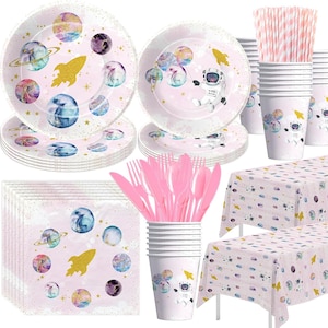 May include: A pink and white space-themed party set with plates, napkins, cups, forks, spoons, knives, and a tablecloth. The set features a pink background with planets, stars, and an astronaut.