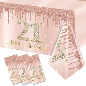 May include: A pink and gold table cover with a glittery finish and the text "Happy 21st Birthday". The table cover is decorated with a diamond-like design and a dripping effect. The table cover is also available in a set of napkins with the same design.