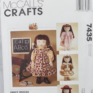 May include: McCall's Crafts pattern for Emma doll dresses. The pattern includes instructions for various fancy frocks and a coat, designed to fit 45cm dolls. The image shows a doll in a red and white dress.