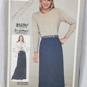 May include: A Simplicity 9711 sewing pattern envelope featuring a beige long-sleeve top and a blue skirt. The cover displays a model wearing the outfit, a waist measurement of 64 cm, and the text Yes I can! learn to sew and Oui, je peux! apprendre à coudre.