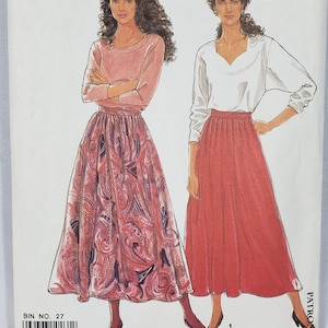 Könnte beinhalten: Ein Simplicity-Schnittmusterumschlag, Nummer 9818, für die Größen 10-20. Die Vorderseite zeigt Illustrationen von zwei Outfits: eines mit einem rosafarbenen Langarmshirt und einem rosafarbenen Paisleymuster-Rock, das andere mit einem weißen Oberteil.