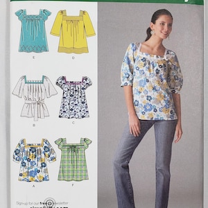 May include: Simplicity sewing pattern 2931 for a square-neck blouse with various sleeve and fabric options. The envelope displays six design variations, including solid colours and floral prints, with size range P5 12, 14, 16, 18, 20.