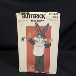 May include: A vintage sewing pattern featuring Bugs Bunny. The pattern is for a Bugs Bunny costume and includes a white shirt, black pants, and a Bugs Bunny head. The pattern is from Butterick and is number 6348. The pattern is for one size.