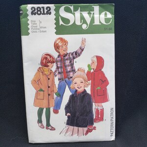 May include: A vintage sewing pattern for children's coats. The pattern includes three different styles: a brown coat with a hood, a plaid shirt, and a red coat with a hood. The pattern is for size 5, chest 61 cm, and is labelled "Style 2812".