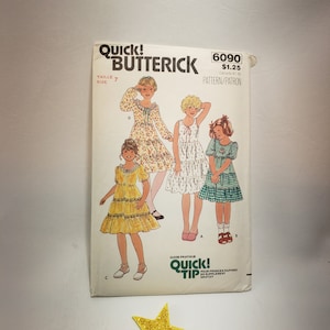 May include: A vintage sewing pattern for girls' dresses. The pattern is for sizes 7 and includes three different styles: a white dress with floral print, a yellow dress with ruffles, and a green and white gingham dress. The pattern is from Quick & Easy Butterick and has the number 6090.