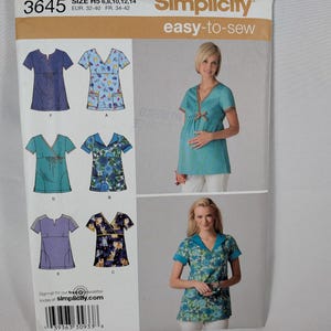 May include: Simplicity 3645 easy-to-sew pattern envelope for tops in sizes H5 6, 8, 10, 12, 14. The front displays six variations of short-sleeved tunics with V-necklines, including solid, floral, and cat-print designs, shown on two models.