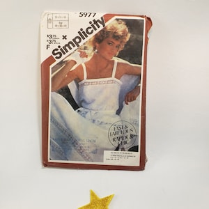 May include: A Simplicity sewing pattern with a model wearing a white tank top with a floral trim. The pattern number is 5977 and the price is $3.75. The pattern is labeled "Fast & Fabulous, Rapide & Chic".