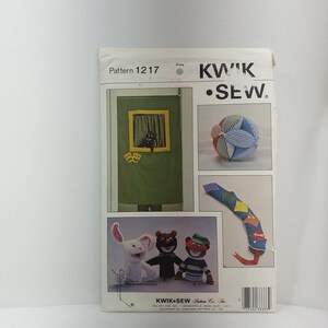 Könnte beinhalten: Ein Nähmuster für eine Puppenbühne mit einer Puppenbühne, drei Puppen, einem Ball und einer Schlange. Das Muster stammt von Kwik Sew Pattern Co. Inc. und trägt die Nummer 1217.
