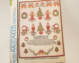 May include: A blue transfer pattern for cross-stitch embroidery featuring a variety of Christmas motifs, including angels, wreaths, trees, reindeer, and a Santa Claus. The pattern is titled "A Sample of Christmas" and includes instructions for completing the project.