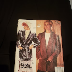 May include: A sewing pattern for a brown leather jacket with a tie belt. The pattern is from McCall's and is for sizes Miss. The pattern is called "Tandy Leather Company".
