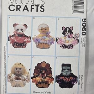 以下が含まれることがあります： McCall's Craftsのパターン封筒。6種類の装飾的なお菓子バスケットのデザインが特徴です。デザインには、パンダ、ひよこ、猫、天使、七面鳥、フランケンシュタインのモンスターが含まれます。「Dreams 'n Delights Original Treat Baskets」というテキストも表示されています。