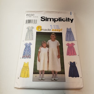 Puede incluir: Patrón de costura Simplicity número 8030 para vestidos de niña en tallas 7, 8, 10 y 12. El patrón incluye seis estilos de vestidos diferentes, incluyendo un vestido blanco con ribete de encaje, un vestido amarillo con bolsillos y un vestido de cuadros azules y blancos. El patrón se titula "made easy!" e incluye instrucciones para hacer los vestidos.