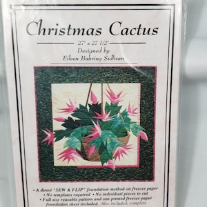 May include: A packaged quilt pattern titled "Christmas Cactus" designed by Eileen Bahring Sullivan. The pattern includes a full-size reusable pattern and a printed freezer paper foundation sheet. The finished quilt size is 68.6cm x 69.9cm.