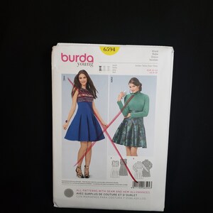Puede incluir: Patrón de costura Burda Young número 6594 para un vestido. El patrón incluye dos estilos de vestidos diferentes, uno con una falda azul y el otro con una falda estampada en verde y negro. El patrón es para las tallas EUR 33-42, US 6-18.