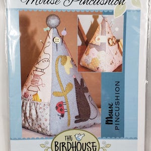 May include: A Mouse Pincushion sewing pattern from The Birdhouse Patchwork Designs. The pattern shows a cone-shaped pincushion with a mouse, flowers, and sewing-related motifs. Measurements are in centimetres.