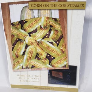 May include: A package for a corn on the cob steamer. The image shows cooked corn on the cob. The text reads "CORN ON THE COB STEAMER" and "Handy bag to Steam Corn on the Cob in the microwave!" with a website address.