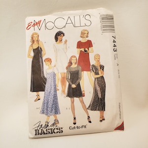 May include: A sewing pattern for five different dresses. The pattern is called "Easy McCall's Fashion Basics Cut-to-Fit" and the pattern number is 7443. The dresses are in various colors and styles, including black, red, white, and blue.