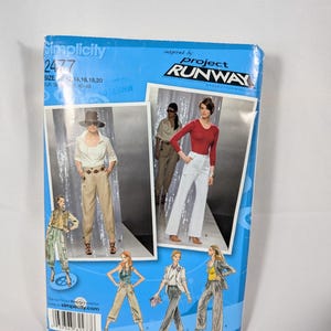 May include: A blue Simplicity 2477 sewing pattern envelope for Project Runway. The front displays illustrations and photographs of various trousers and tops, including beige trousers, white trousers, and blazers. It lists sizes 12, 14, 16, 18, 20.