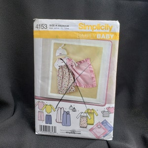 May include: Simplicity pattern 4153 for a baby outfit. The pattern includes a dress, a hat, a blanket, and a sleep sack. The pattern is for sizes XXS, XS, S, and M. The pattern is for Simply Baby.