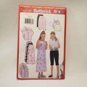 May include: A sewing pattern for girls' clothing, featuring a white top, a purple top, a pink skirt, a floral skirt, and black pants. The pattern is for sizes 7-8-10. The pattern is from Butterick and the pattern number is 6038.