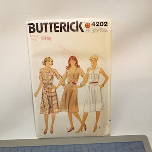 May include: A vintage sewing pattern for a dress, Butterick pattern number 4202, size 6-8-10. The pattern shows three women wearing different styles of dresses, one with a plaid pattern, one with a solid brown color, and one with a white pattern.