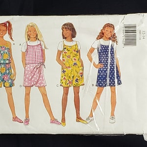 May include: A sewing pattern for girls' clothing, featuring four different styles of dresses and shorts. The pattern is from Butterick, and the size is 12-14. The pattern includes instructions for making a floral print dress, a gingham print dress, a floral print jumpsuit, and a polka dot dress.