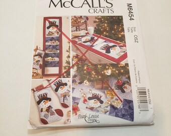 May include: A sewing pattern for a snowman-themed Christmas stocking, table runner, and wall hanging. The pattern is from McCall's Crafts and is designed by Pearl Louise Designs.