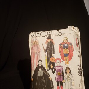 May include: A vintage McCall's sewing pattern for children's Halloween costumes. The pattern includes five costumes: a witch, a vampire, a ghost, a superhero, and a princess. The pattern number is 7316 and the size is X-Small.